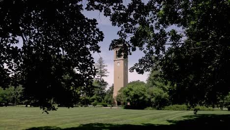Stanton-Memorial-Carillon-Campanile-on-the-campus-of-Iowa-State-University-in-Ames,-Iowa-with-gimbal-video-walking-forward-through-trees