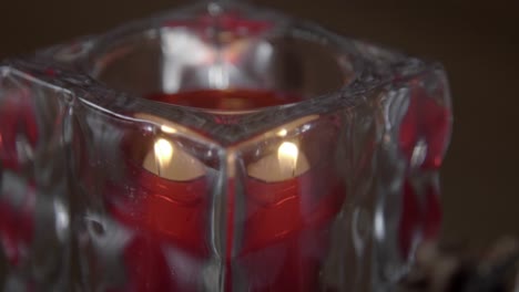 Close-up-of-small-red-tea-light-flame-flickers-in-a-glass-holder