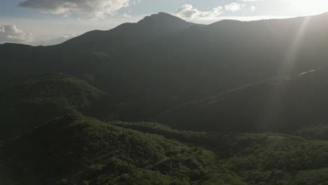 Paso-Elevado-De-La-Exuberante-Y-Exuberante-Selva-Montañosa-Verde,-Destello-De-Lente-Desde-El-Sol-Bajo