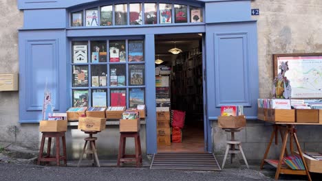 A-French-second-hand-bookstore-with-a-blue-storefront,-displaying-many-books