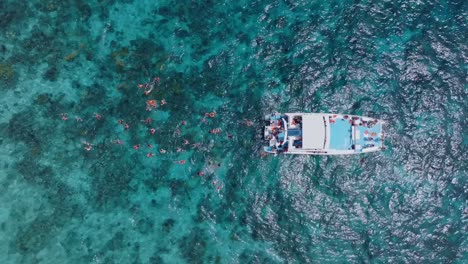 Gente-Buceando-Sobre-Arrecifes-De-Coral-En-Agua-De-Mar-Turquesa,-Elevación-Aérea