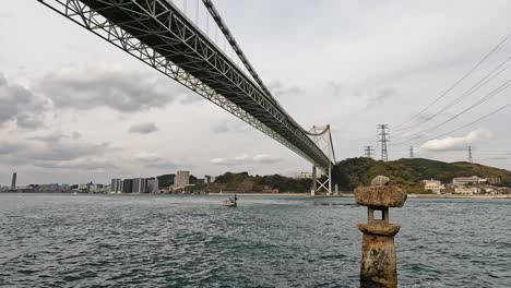 Old-japanese-rock-lantern-halfly-submerged-in-water-in-front-of-Kanmon-bridge-and-the-kanmon-strait-in-between-the-japanese-island-Honshu-and-Kyushu