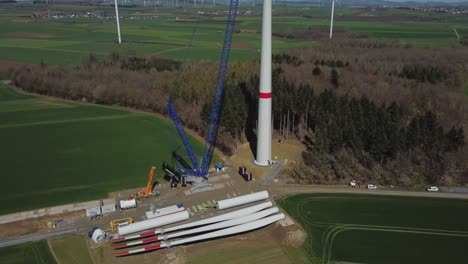Wind-Turbine-During-Construction-With-Different-Windmill-Parts-On-The-Ground---aerial-drone-shot