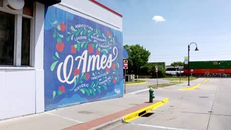 Downtown-Ames,-Iowa-wall-mural-with-train-moving-in-distance-and-stable-video