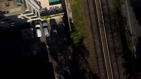 Parking-next-to-the-railway,-sun,-shadows,-drone-takes-off