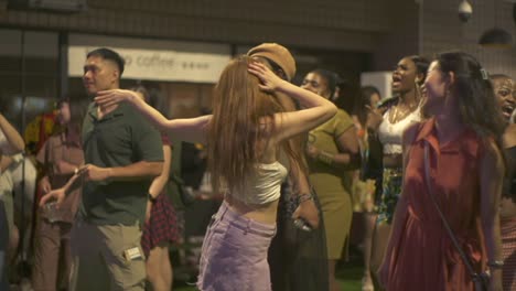 Asian-woman-dancing-ecstatically-at-ethnic-cultural-music-festival-event,-filmed-as-medium-shot-in-handheld-slow-motion-style