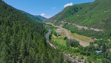 Luftaufnahme-über-Einem-Bewaldeten-Tal-Mit-Einer-Straße-Durch-Die-Mitte-In-Der-Nähe-Des-Crested-Butte-Mountain,-Colorado,-USA