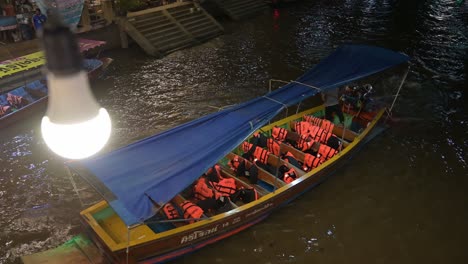 An-empty-wooden-boat-is-being-steered-by-a-lone-boatman-to-the-upper-right-side-of-the-frame,-in-the-canal-of-Amphawa-Floating-Market,-Samut-Songkhram,-Thailand