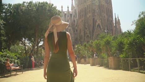 Atemberaubendes-Video-Einer-Jungen-Kaukasischen-Frau-In-Einem-Grünen-Kleid-Mit-Strickmütze,-Die-Zu-Einem-Unglaublichen-Wahrzeichen-Geht-–-Der-Sagrada-Familia-In-Barcelona
