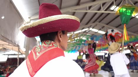 Slow-motion-shot-of-a-man-wearing-a-red-hat-whilst-people-dancing-at-the-Guelaguetza