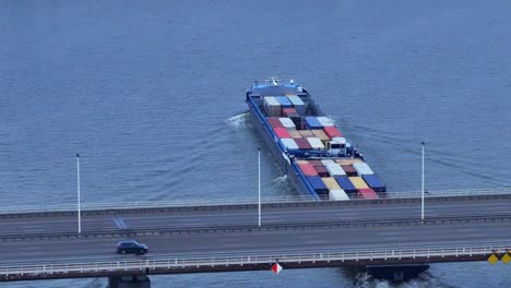 Aerial-View-Of-Olesia-Cargo-Container-Ship-Sailing-Underneath-Moerdijk-Bridge-With-Traffic-Driving-Across