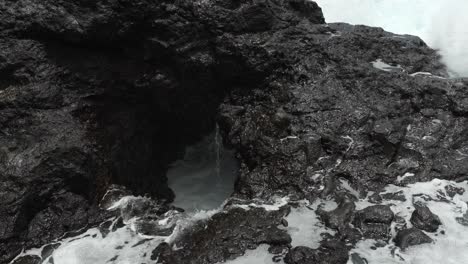Waves-crashing-against-volcanic-cliff-rocks-of-Tenerife,-creating-white-foam
