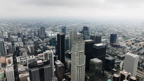 Aerial-view-backwards-over-high-rise-in-downtown-Los-Angeles,-cloudy-day-in-USA