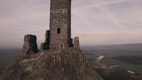 Tilting-up-drone-view-revealing-medieval-Hazmburk-Castle-hilltop-tower-ruin
