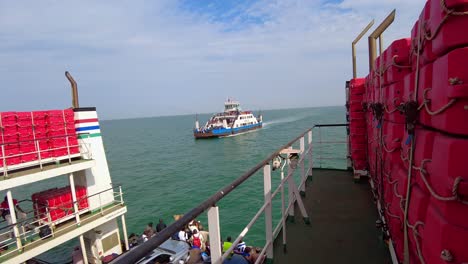 Kunta-Kinteh-ferry-approaching-and-passing-by-Kanilai-ferry-both-transporting-people-and-vehicles-at-sea-in-Gambia,-West-Africa