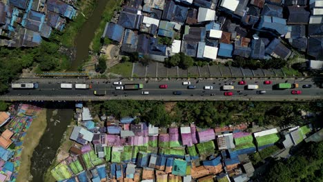 top-view-of-cars-on-the-road-in-the-middle-of-two-colorful-villages---Jodipan-"rainbow"-village-and-the-blue-city---Malang,-East-Java---Indonesia