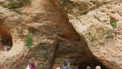 Tourists-exploring-sandstone-Gutmans-Cave-with-old-inscriptions-on-walls,-Latvia