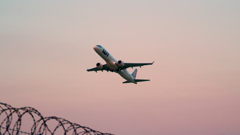 Plane-Departure-from-a-Hostile-Environment-as-Soars-through-Sunset-Sky-and-Beyond-Razor-Blade-Fences