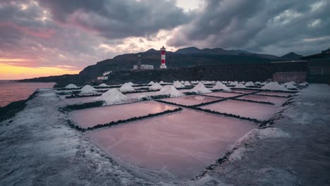 Timelapse-of-Salinas-de-Fuencaliente-salt-pans-leading-lines-and-lighthouse-during-colorful-sunset-with-orange-and-red-clouds