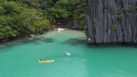 Captivating-Aerial-of-Tourists-Engaging-in-Kayaking-and-Swimming-at-Emerald-Cadlao-Lagoon,-El-Nido