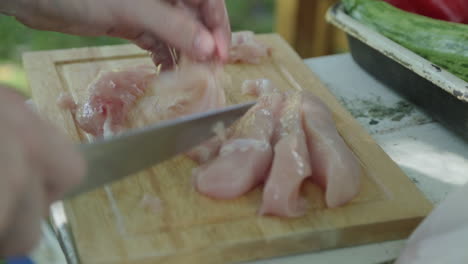 Outdoor-camping-or-barbecue-preparation-cutting-chicken-with-knife-before-cooking
