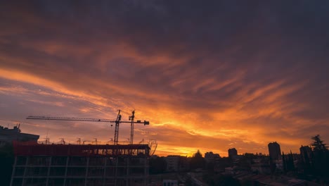 Vide-angle-view-timelapse-spectacular-and-colorful-sunset-with-clouds-in-a-city-with-constructions-works-as-foregorund-cranes-and-scaffoldings
