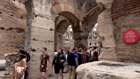 Sightseeing-tourists-walking-into-the-Amphitheatre-of-the-Coliseum,-Rome,-Italy
