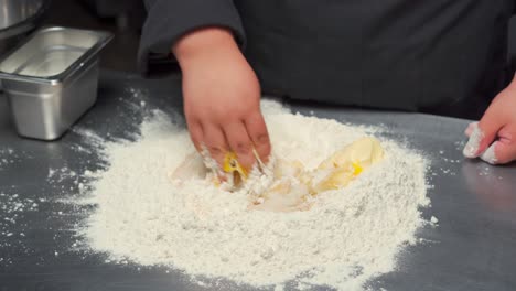 Gourmet-restaurant-kitchen-chef-baker-mix-dough-with-bare-hands-fluor-yolk-eggs-butter-salt-sugar-yeast-traditional-way-recipe-bread