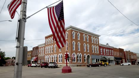 Antique-four-way-stop-light-and-American-flag-in-downtown-Toledo,-Iowa-with-stable-video-close-up-at-an-angle