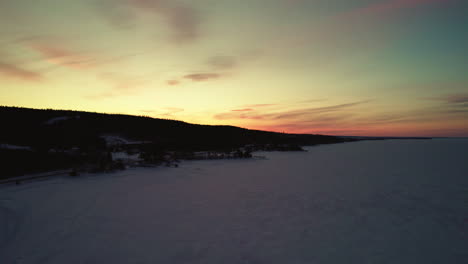 Flying-drone-above-a-frozen-lake-in-canada-at-golden-hour