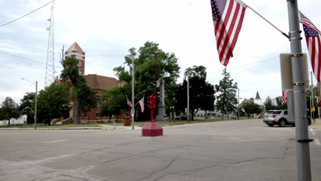 Antique-four-way-stop-light-and-American-flag-in-downtown-Toledo,-Iowa-with-stable-video-wide-shot-at-an-angle