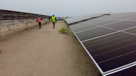 Panoramablick-Auf-Ein-Team-Aus-Schwarzafrikanischen-Ingenieuren-Und-Technikern,-Die-Auf-Dem-Gelände-Eines-Photovoltaik-Bauernhofs-Arbeiten-Und-Solarpanel-Arrays-Installieren