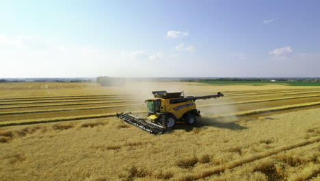 Sidewards-aerial-tracking-shot-of-combine-harvester-harvesting-grain-crops