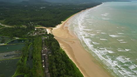 Sandy-beach,-jungle-forest-and-coastline-buildings-in-Thailand,-aerial-view
