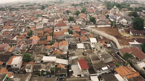 Aerial-flyover-park-beside-poor-slum-district-with-old-houses-in-Jakarta-City,-Indonesia---Establishing-drone-shot