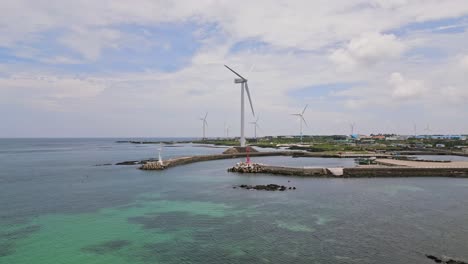Atemberaubender-Drohnenblick-Auf-Die-Unberührten-Ufer-Des-Woljeong-Strands,-Einer-Ruhigen-Oase-Auf-Der-Wunderschönen-Insel-Jeju,-Mit-Einem-Einzigartigen-Blick-Auf-Windkraftanlagen-Direkt-Am-Wasser