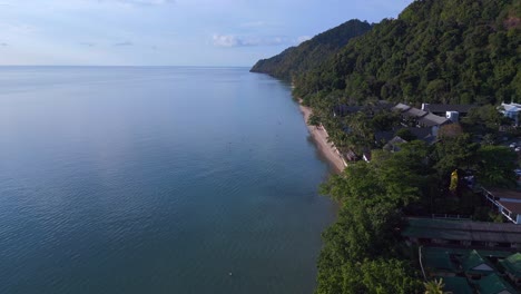 Beautiful-aerial-top-view-flight-Beach-Village-Huts-Resort,-tropical-Bungalows-on-Mountainous-Island-Thailand-2022