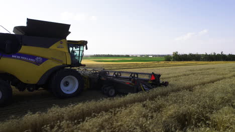 Close-aerial-around-front-of-combine-harvester-harvesting-with-cutting-platform