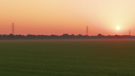 The-sun-rising-over-a-rice-field-in-Arkansas-with-power-lines-in-the-horizon