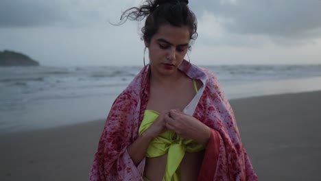 Attractive-Asian-Indian-woman-wearing-beautiful-yellow-dress-standing-at-the-beach-and-looks-at-the-ring-on-her-finger-hand,-Female-tourist-on-summer-vacation