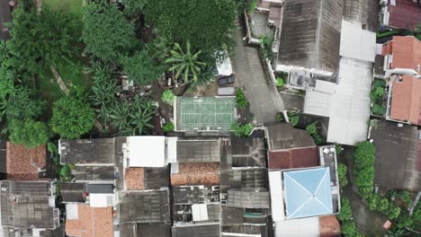 Aerial-top-down-shot-showing-slum-area-of-Jakarta-with-amateur-sport-field-during-sunny-day