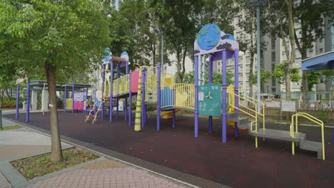 Reveal-behind-tree-to-empty-colorful-global-playground-gym-set-with-no-children-in-down-town