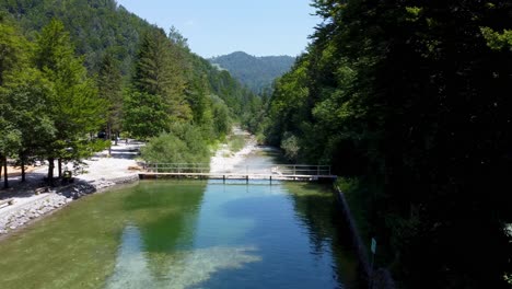 Luftüberführung-Klarer-See,-Brücke-Und-Natürlicher-Fluss-Umgeben-Von-Grünen-Waldbäumen-Im-Globalen-Geopark-Idrija-An-Sonnigen-Tagen,-Slowenien