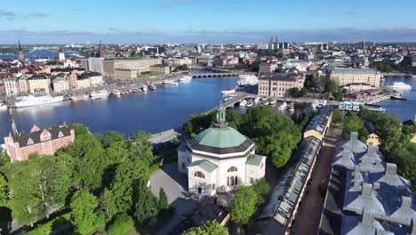Drone-fly-over-event-venue-to-Royal-Palace-and-riverfront-with-historic-buildings,-Stockholm