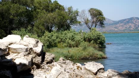 Butrint,-Albania,-view-of-the-lake-shore,-ancient-ruins,-and-mountains-in-the-background