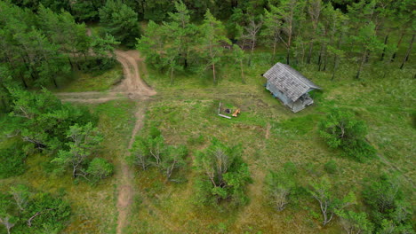 Small-wooden-cabin-home-in-rural-landscape-near-forest,-aerial-drone-view