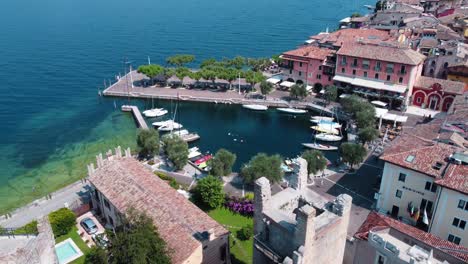 Flying-over-the-castle-of-Torri-del-Benaco-and-revealing-a-picturesque-harbor-at-Lake-Garda