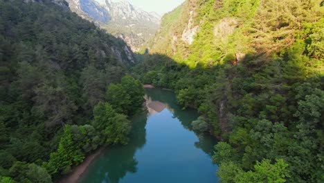FPV-drone-flight-over-beautiful-tranquil-river-surrounded-by-trees-and-mountains---Children-and-people-resting-on-sandy-beach-at-stream-in-Lebanon
