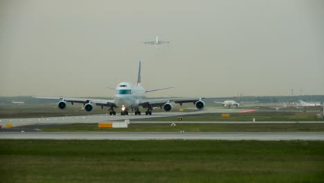 Telephoto-approaching-cargo-airplane-on-runway-and-starting-plane-on-dusty-day