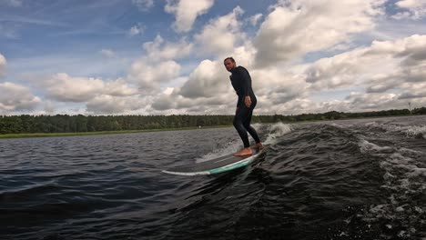 Surfer-Auf-Longboard-Surft-Wellen-Auf-Einem-See-Mit-Wolken-Am-Himmel,-Gefilmt-Mit-GoPro-60fps